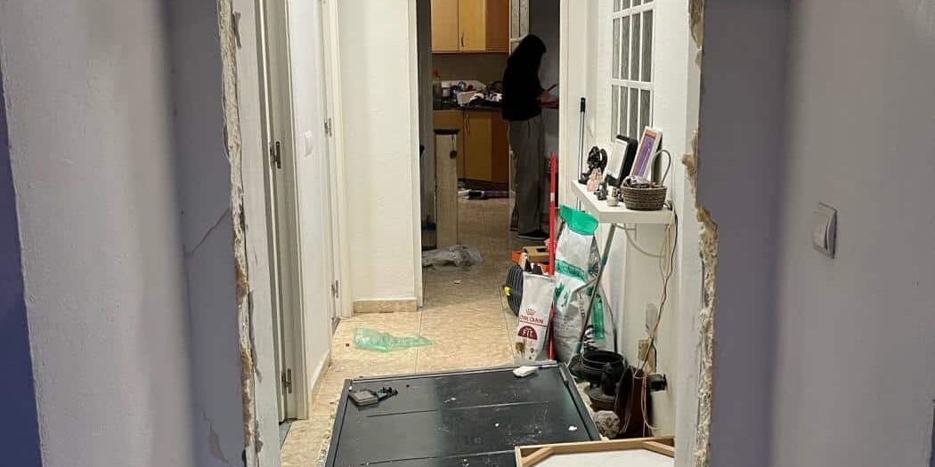Imagen profesional en tonos azul oscuro y gris, con una puerta de vivienda parcialmente abierta, luz entrando desde el exterior y una balanza de justicia en primer plano. Estilo sobrio y corporativo. Texto: “Registro policial en domicilio · Defensa penal