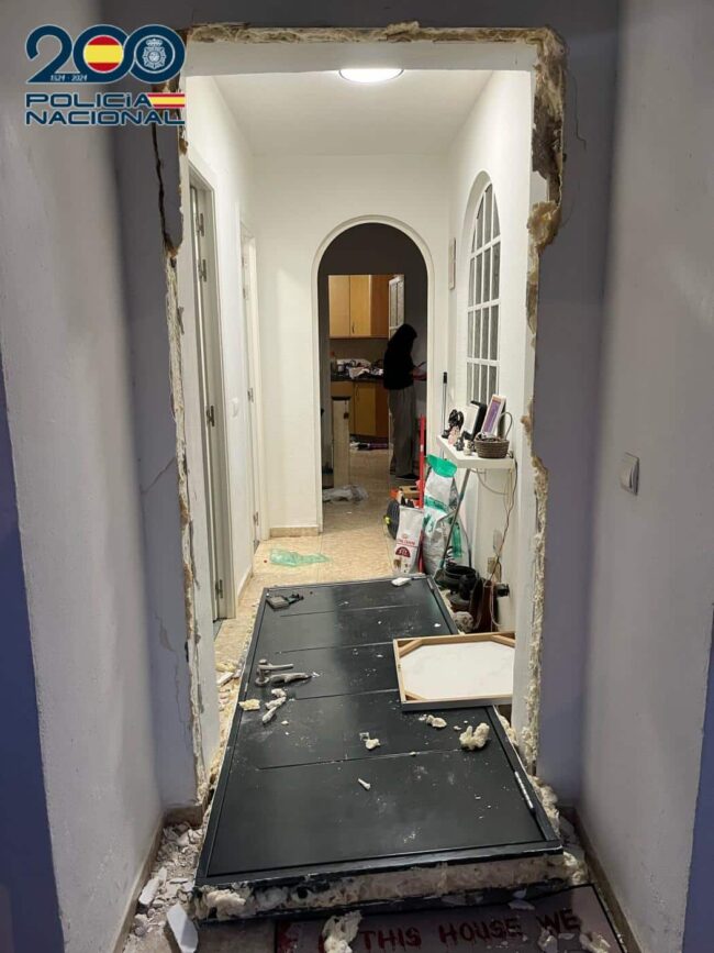 Imagen profesional en tonos azul oscuro y gris, con una puerta de vivienda parcialmente abierta, luz entrando desde el exterior y una balanza de justicia en primer plano. Estilo sobrio y corporativo. Texto: “Registro policial en domicilio · Defensa penal
